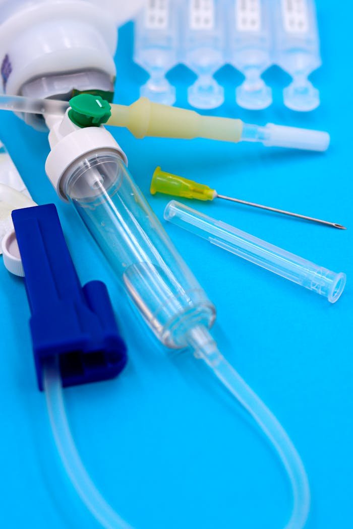 Close-up of medical syringes, needles, and tubes on a blue background.