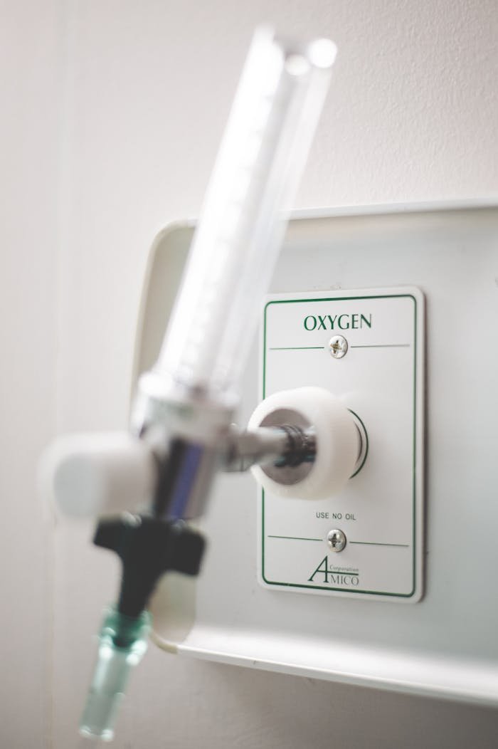 Close-up of a medical oxygen valve in a healthcare setting with blurred background.